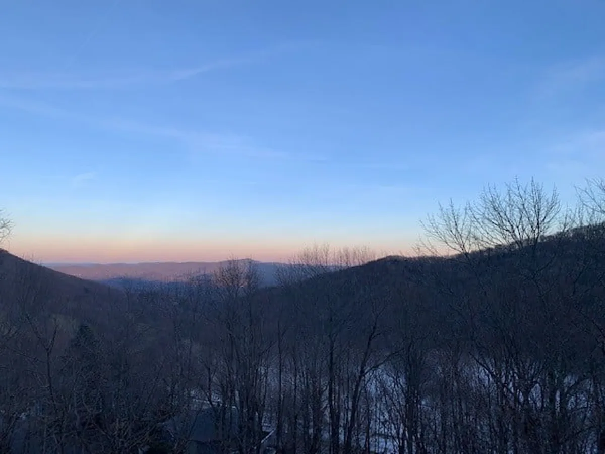 A panoramic view of mountains and sky, framed by trees, suggesting nearby hiking trails and opportunities for nature photography. The scene conveys a sense of adventure, tranquility, and immersion in the High Country landscape.