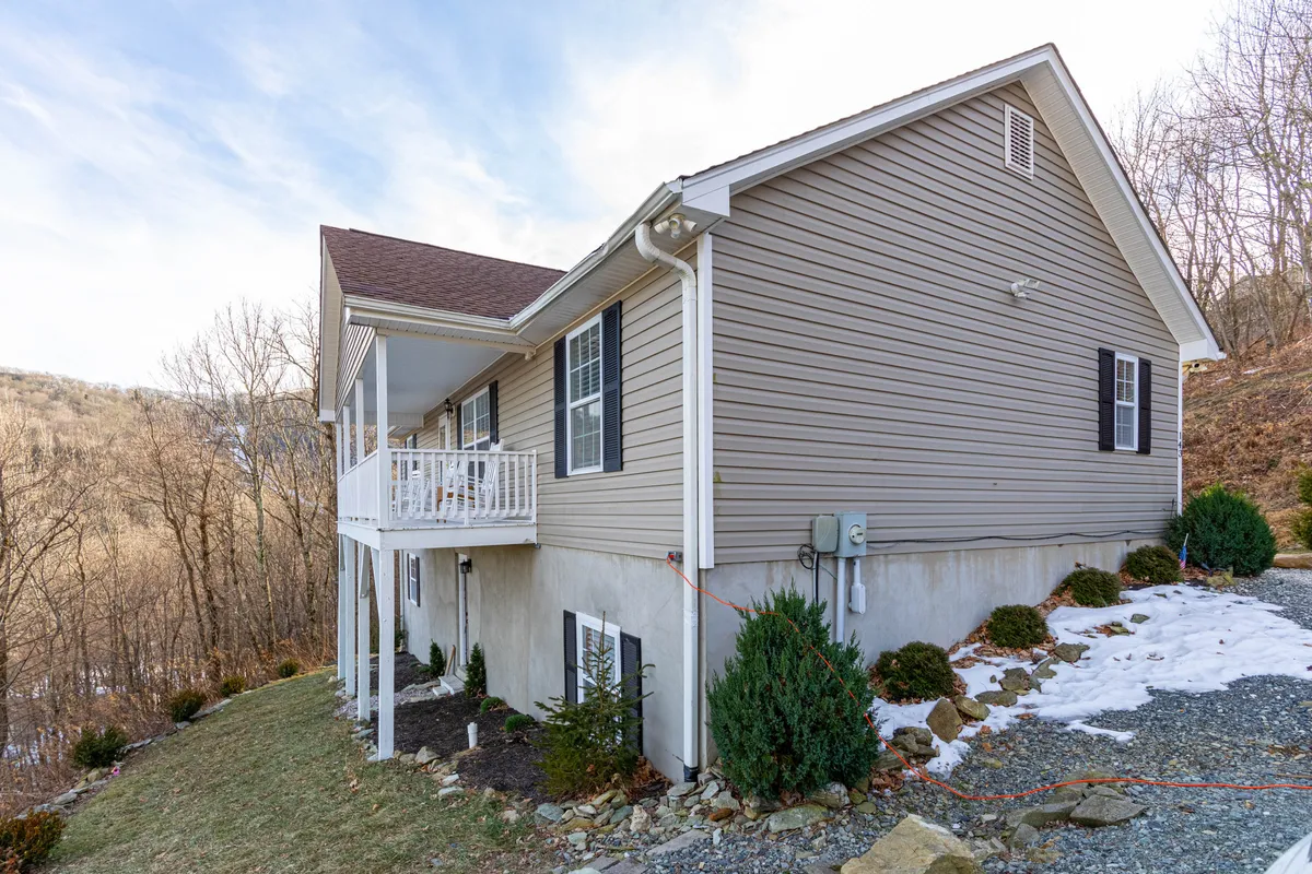 This image shows the exterior of the Seven Devils Sunrise house with its inviting porch and the surrounding natural landscape. The home is nestled in a peaceful mountain setting, with ample space for families to relax outside and take in the scenery.