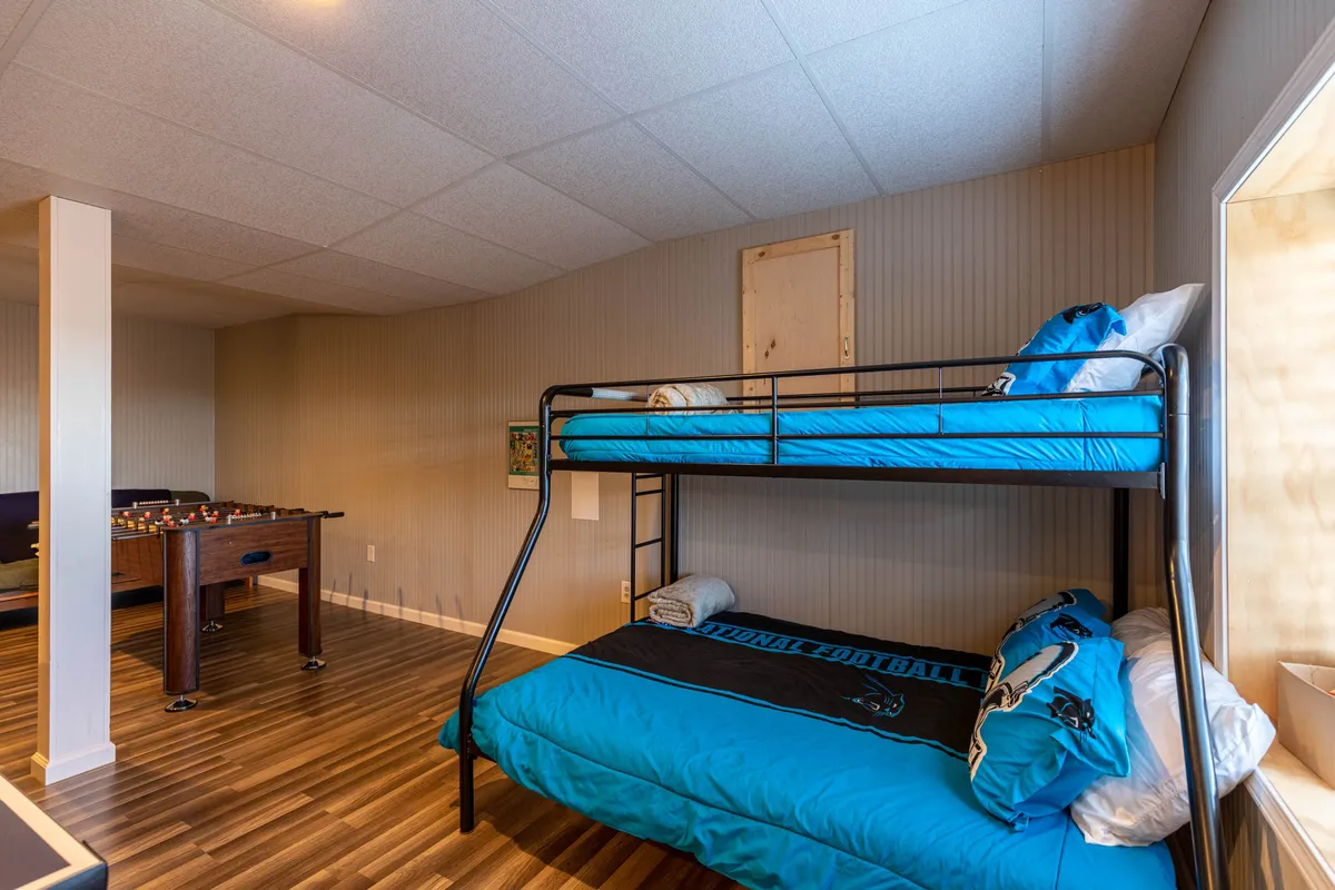 This room features a foosball table positioned next to cozy bunk beds, with inviting textured walls, creating a playful environment for both games and group sleepovers.