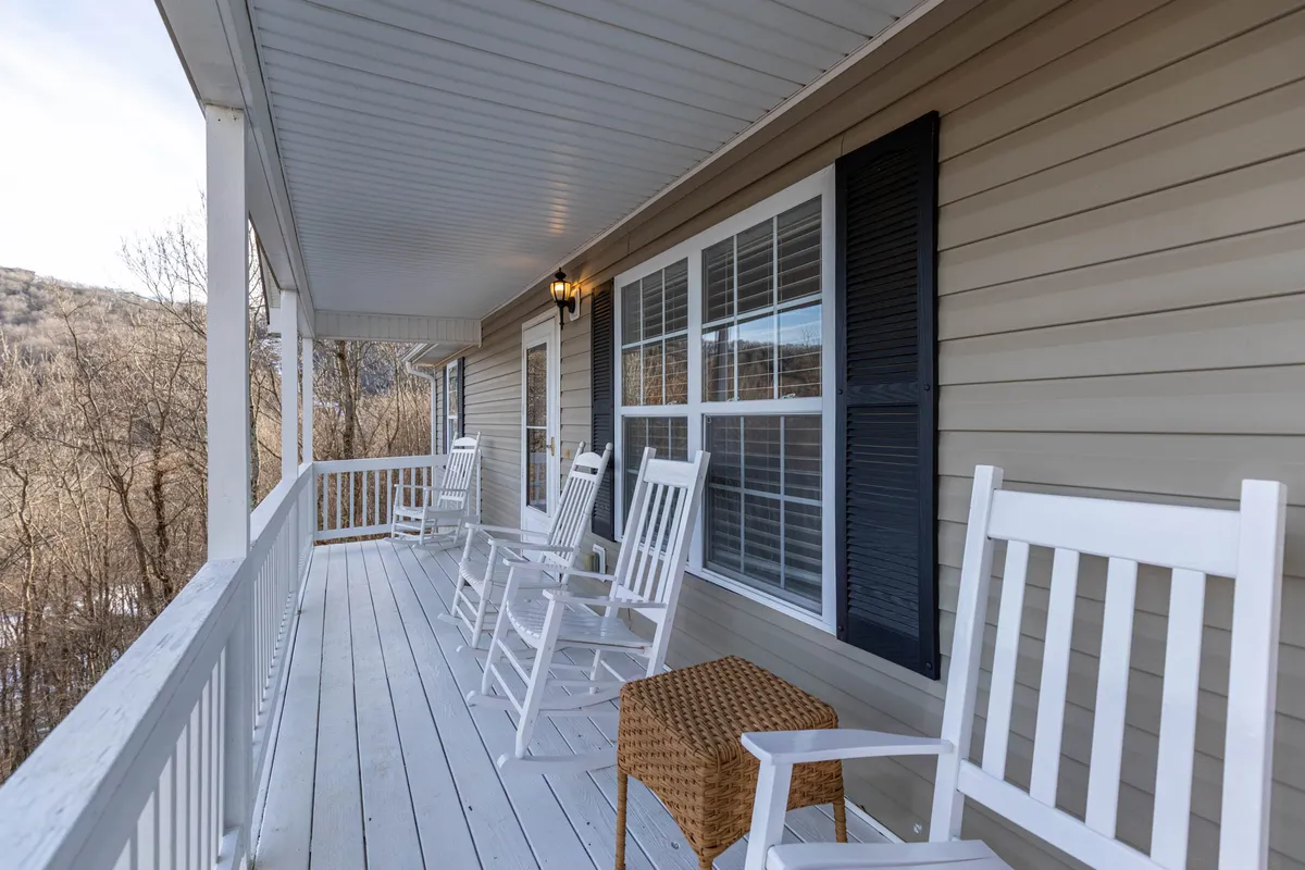 A cozy outdoor porch area with classic rocking chairs facing a sweeping mountain view. The area is accented by woven baskets and features window shutters, creating a relaxed and inviting space perfect for enjoying coffee, reading, or socializing while soaking in the scenery.