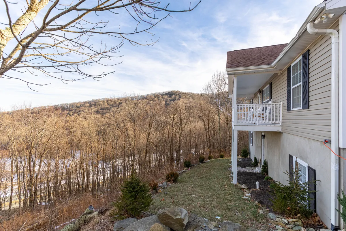 This image features the exterior of the property set against a breathtaking mountain backdrop, with a landscaped garden and views extending into the High Country. The inviting porch and the expanse of natural scenery emphasize the property's connection to outdoor adventure and exploration.